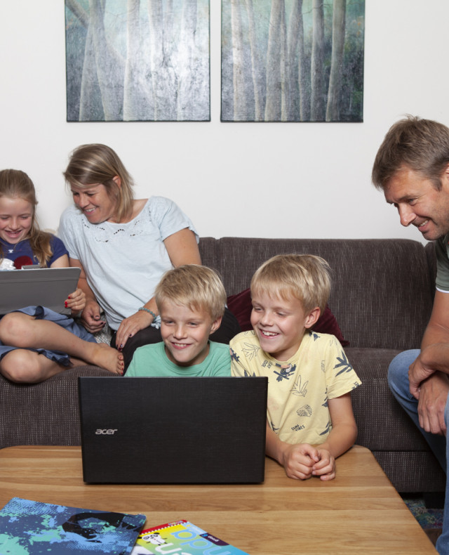 Foto gezin met vader en moeder en 3 kinderen die samen naar 2 laptops kijken